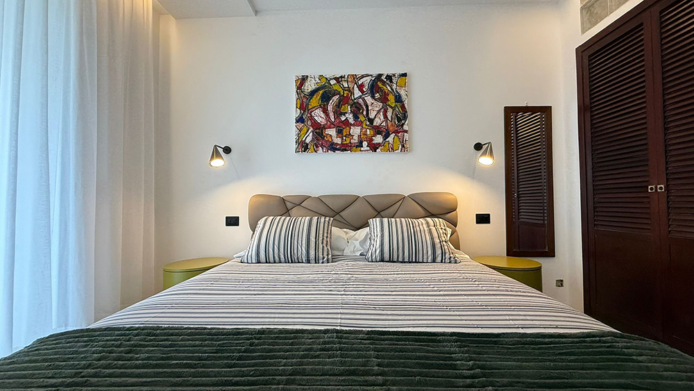 Camera da letto matrimoniale con applique e quadro astratto