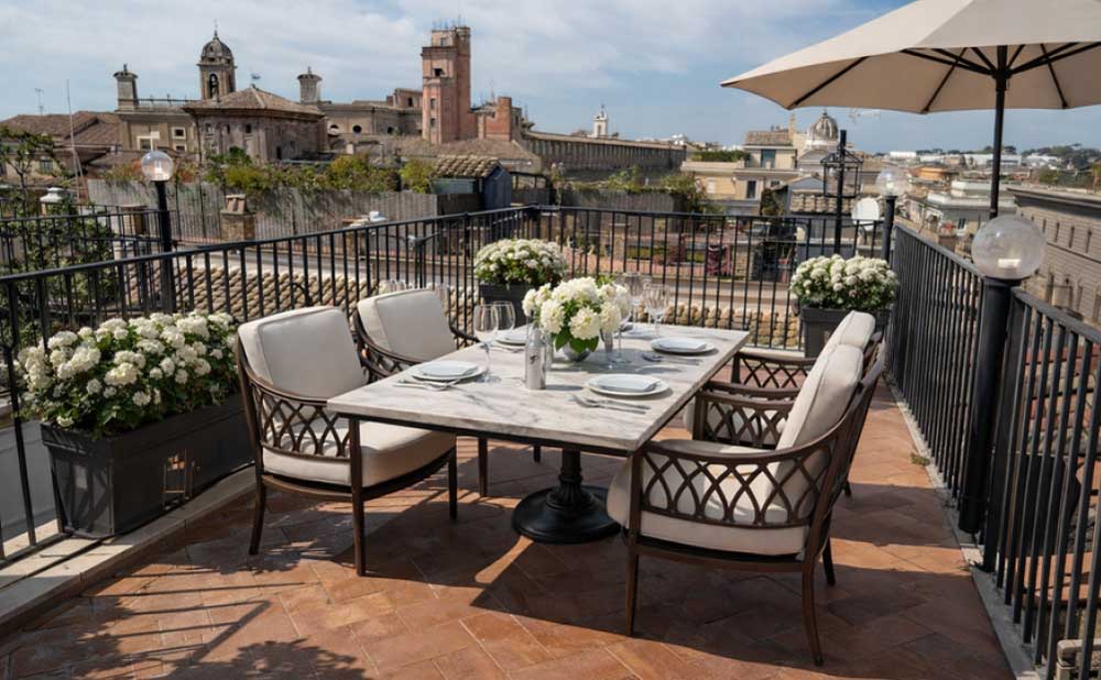 Terrazza arredata con tavolo da pranzo e vista sui tetti e i campanili di Roma